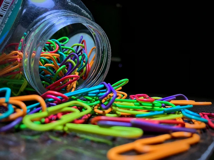 a jar filled with lots of colorful paper clips